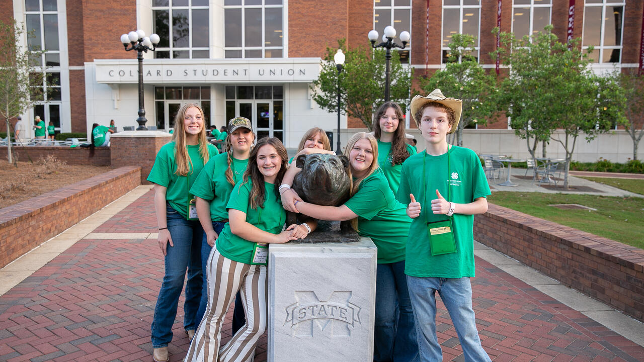 Students in green shirts posing for a picture.