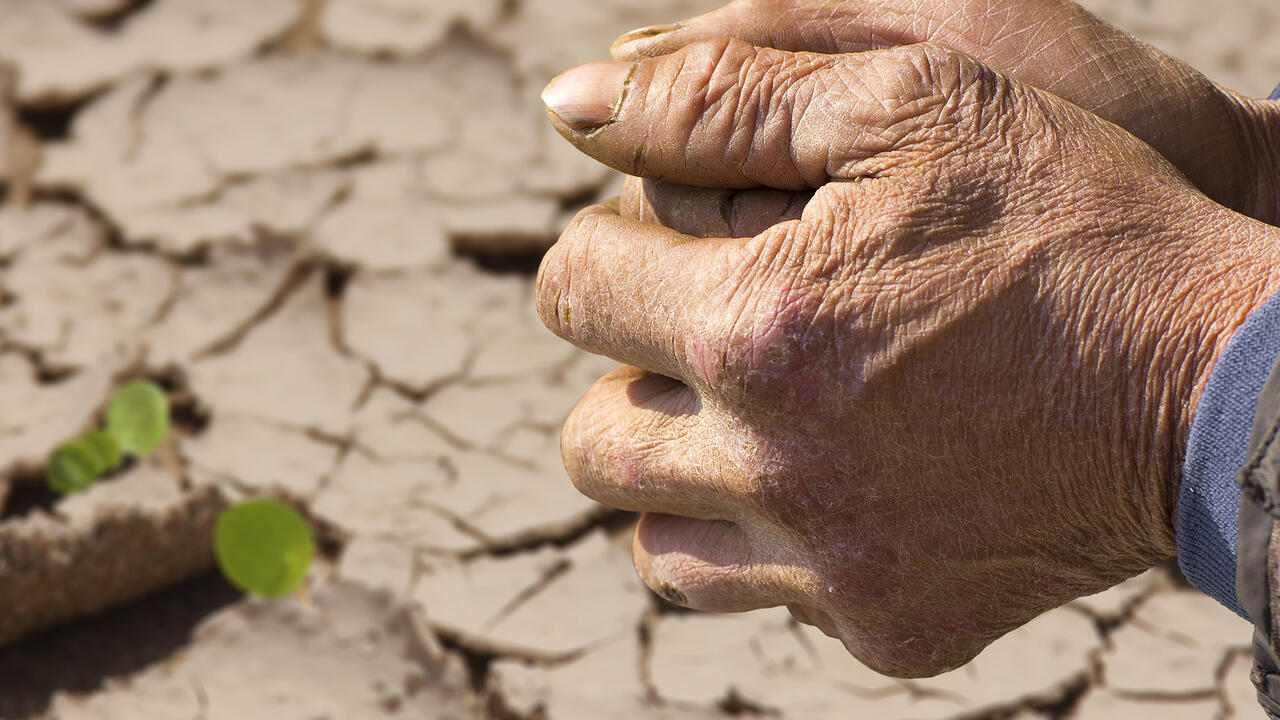 Hands clasped together over a dry field.