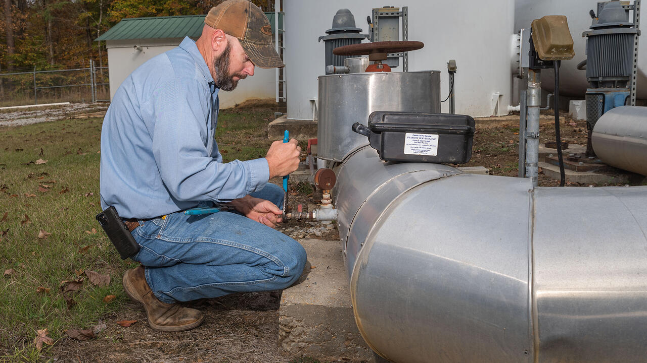 A man adjusts a valve on a water pipe.