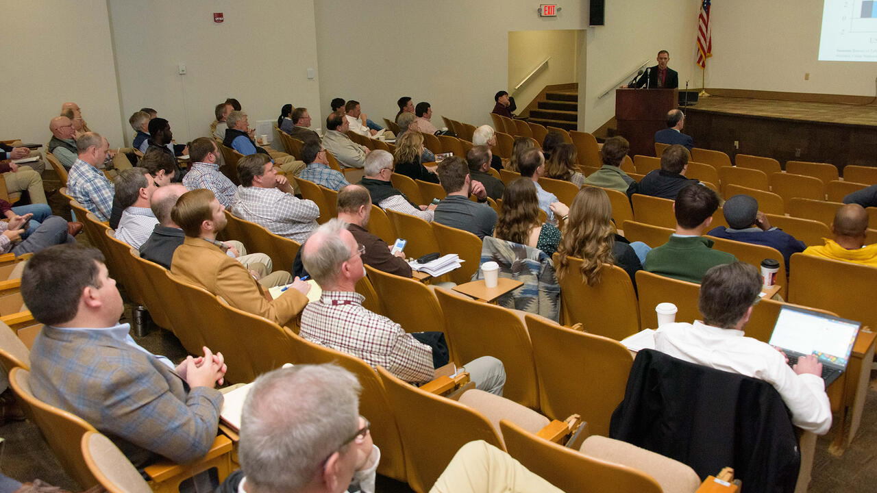 People in an auditorium watching a person give a presentation.