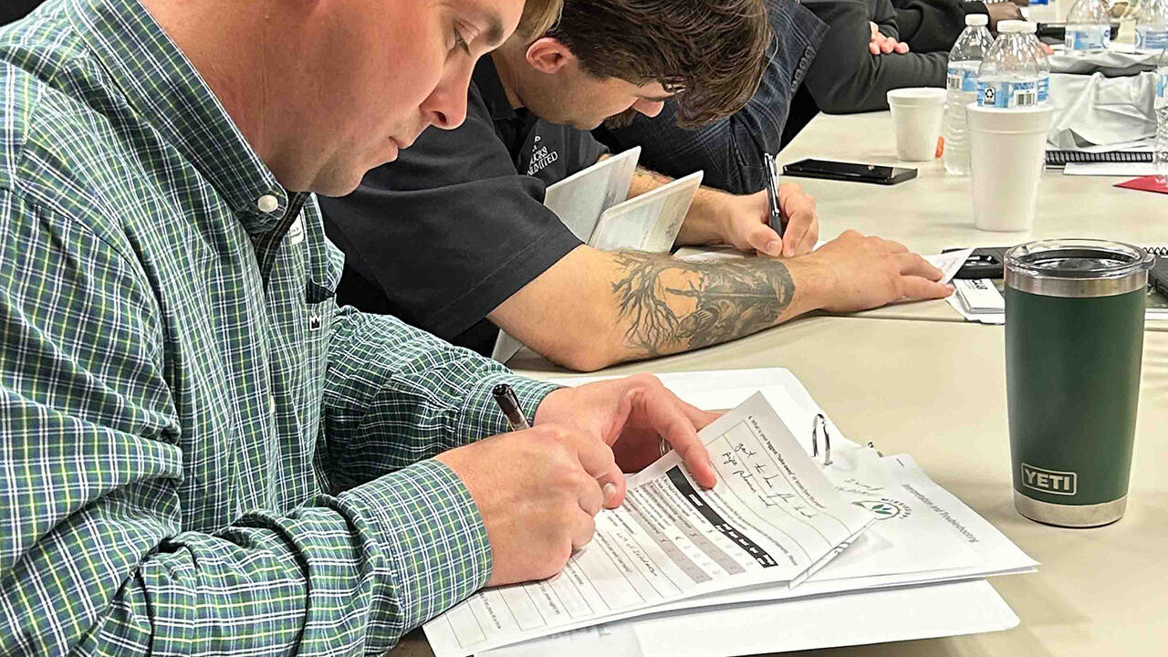Adults do paperwork at tables.