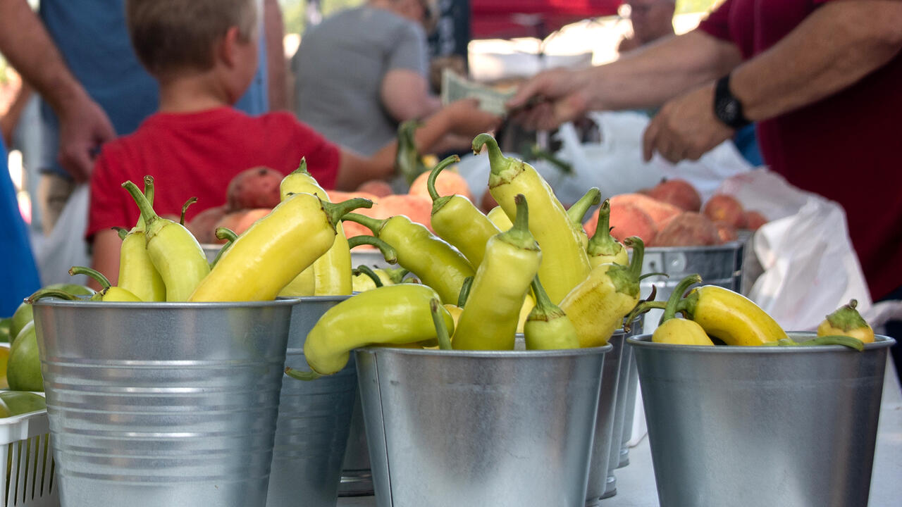 Buckets of peppers stand on a table at a market.