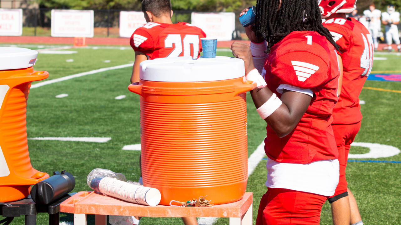 Football player getting water from a cooler.
