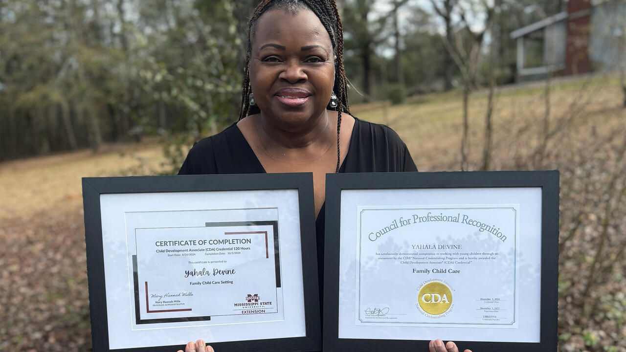 A woman holds two framed certificates.