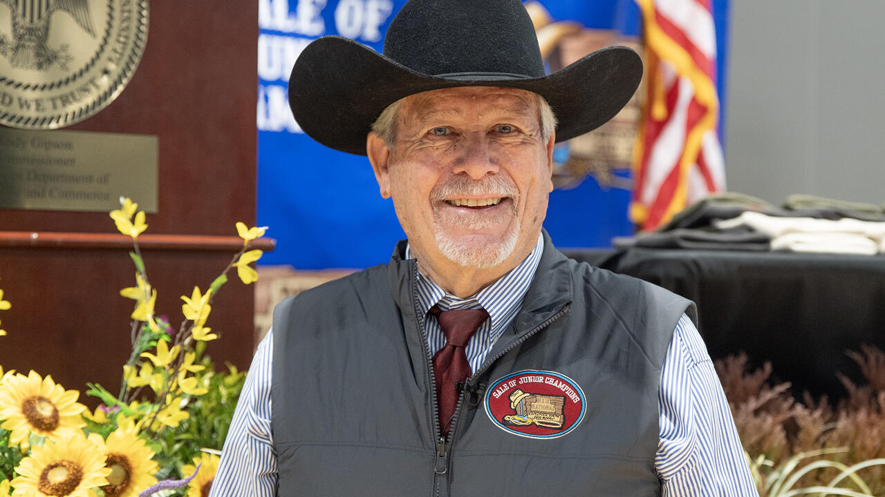 Auctioneer wearing a cowboy hat is smiling.