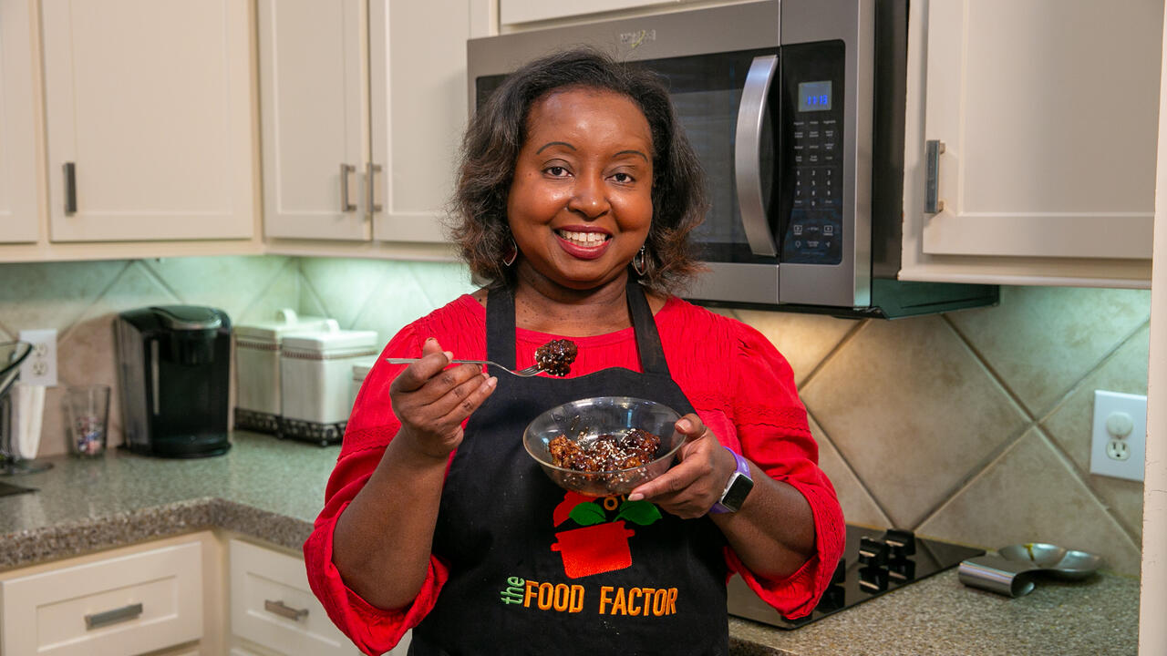 A woman holds a bowl of Teriyaki Meatballs.