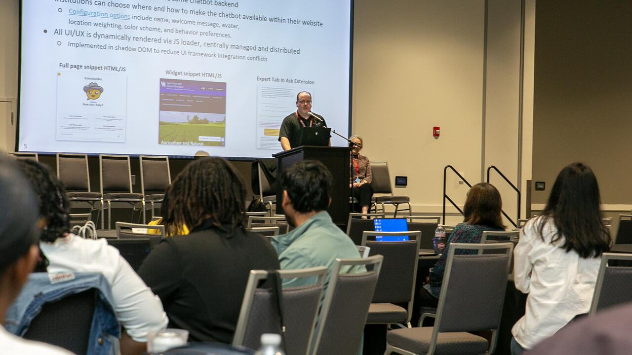 Two people are on stage during a presentation.