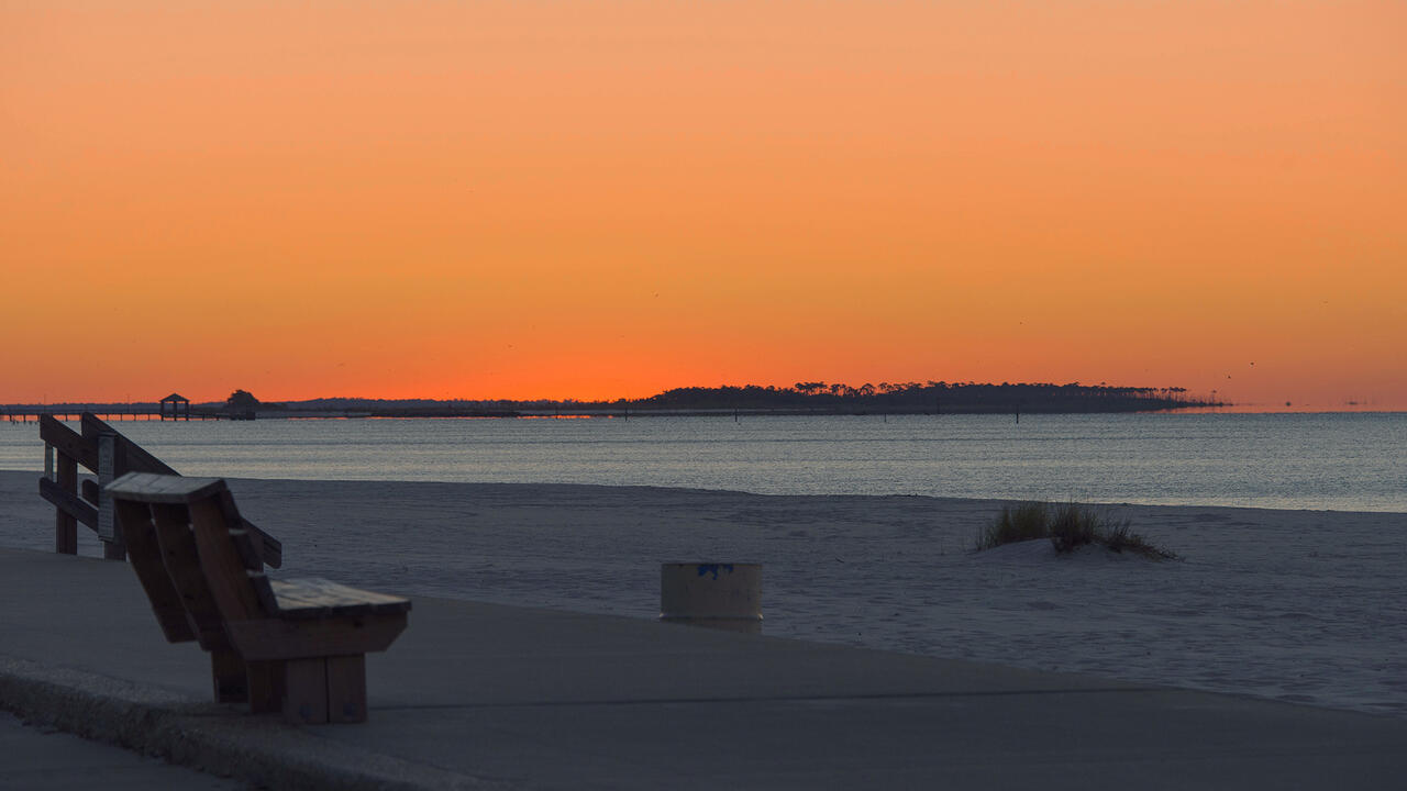 An orange sunset on Biloxi beach with the Gulf of Mexico in the background.