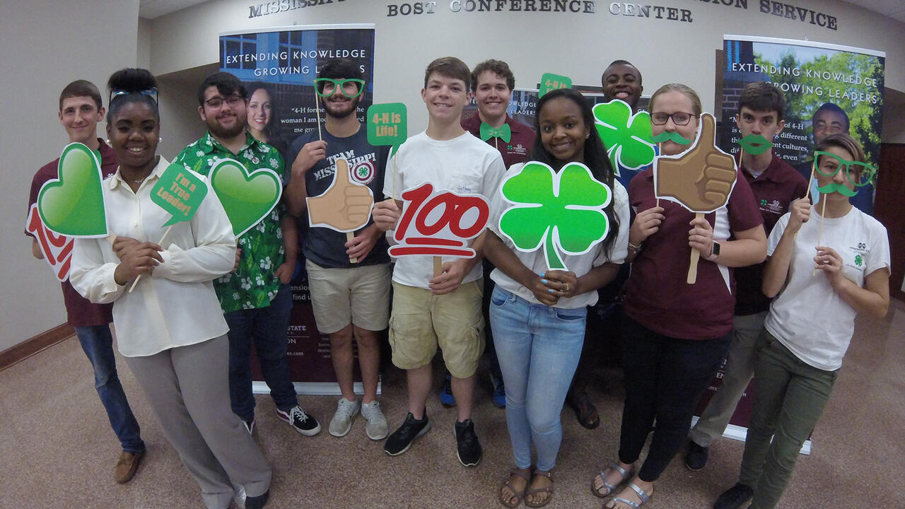 A diverse group of youth displaying 4-H signs.