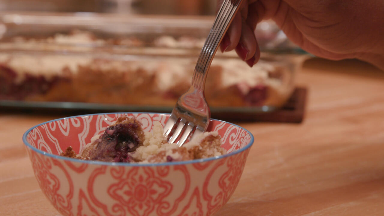 a small bowl with a serving of fruity French toast casserole with a 9x13 pan in the background