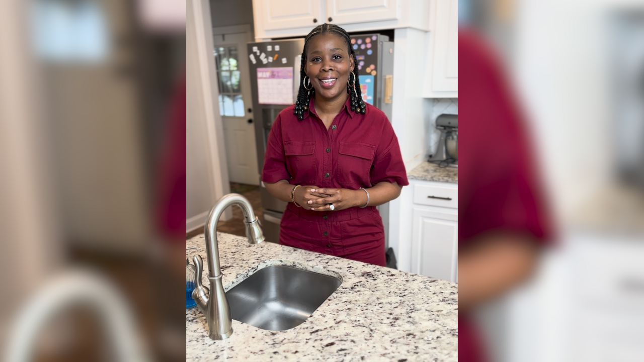 A woman stands at the kitchen sink.