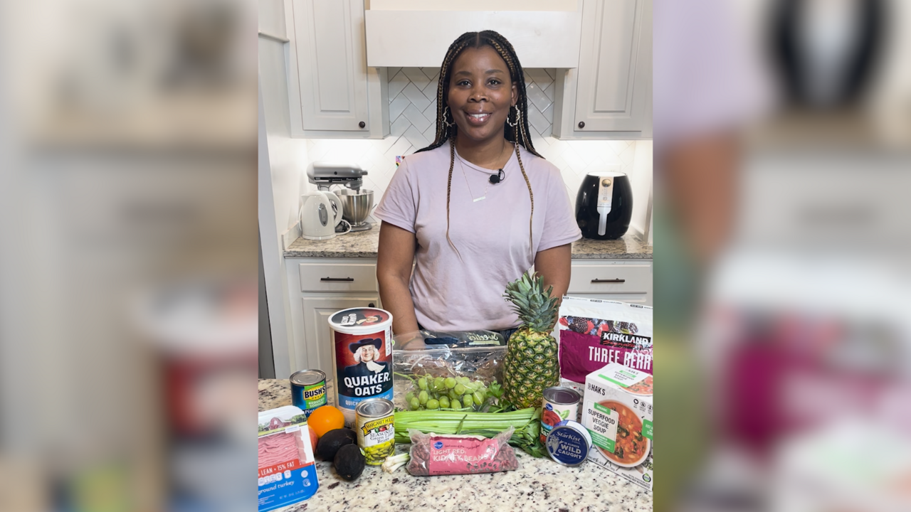 A woman stands in front of a kitchen counter filled with food products.