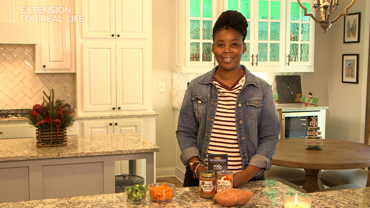 A woman stands at a kitchen counter with ingredients displayed.