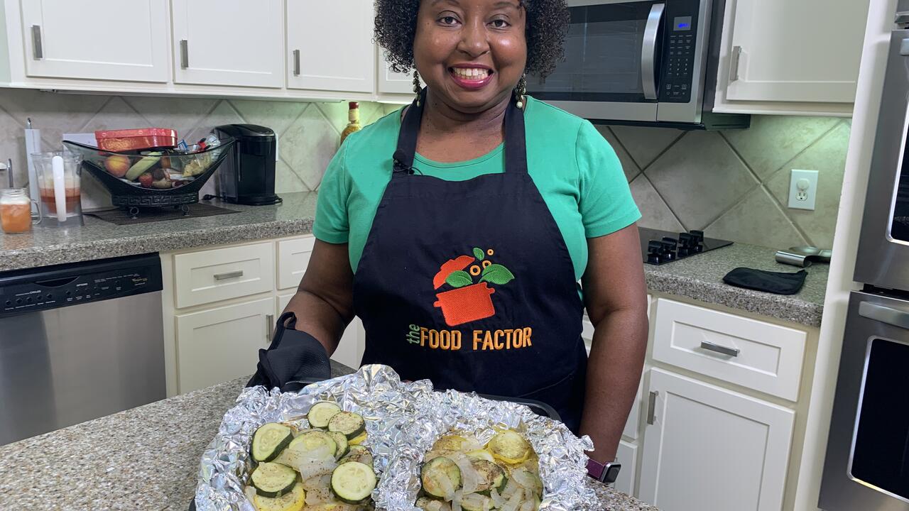 A woman stand in a kitchen with prepared food.