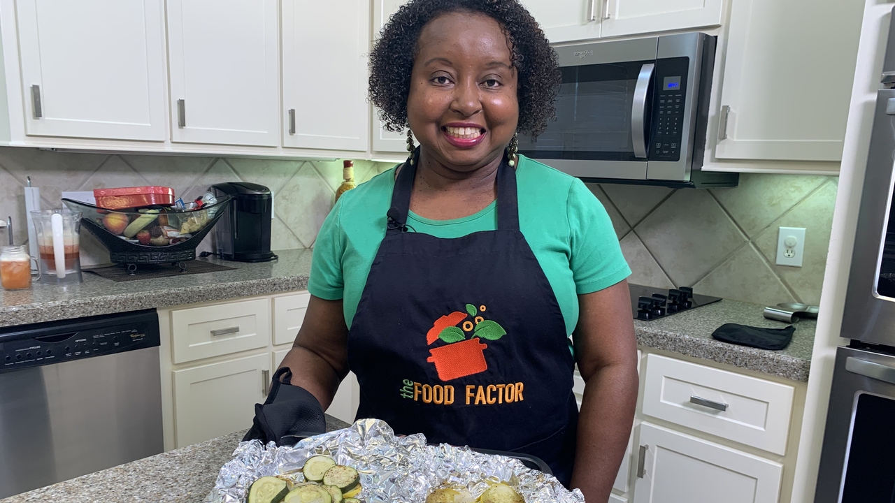A woman stand in a kitchen with prepared food.