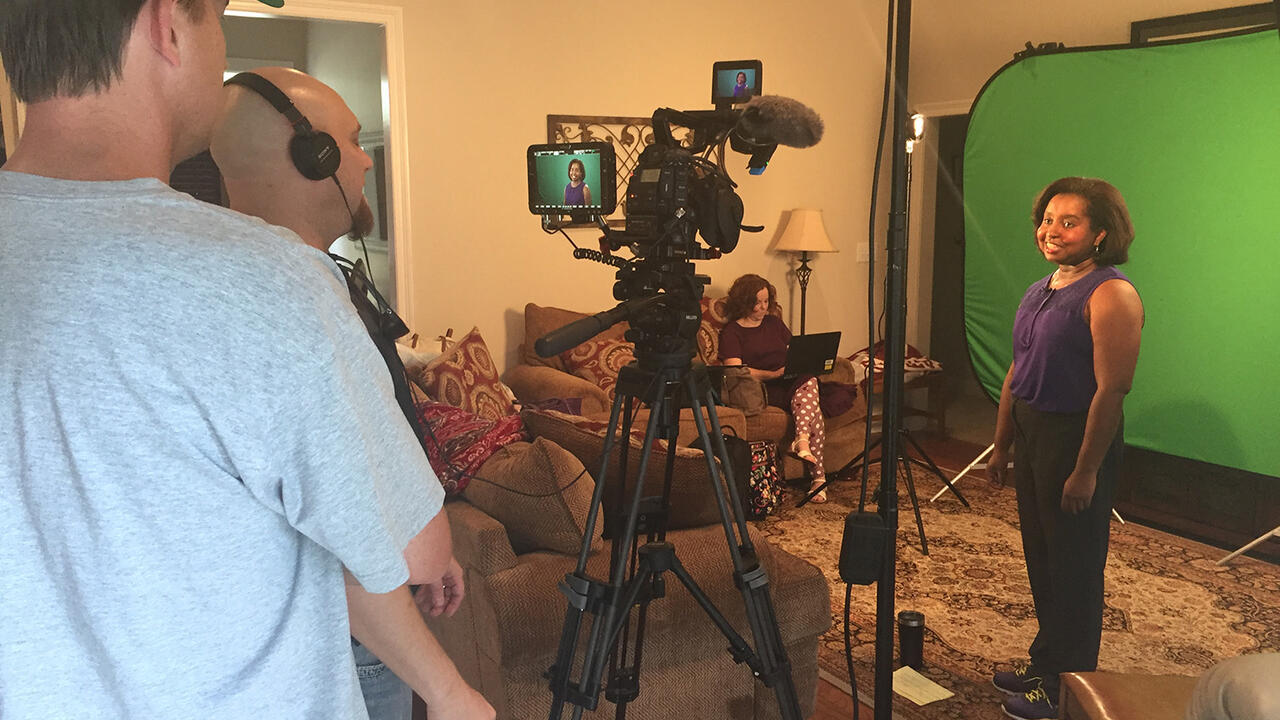 Host Natasha Haynes stands in front of a green screen filming a scene for The Food Factor.