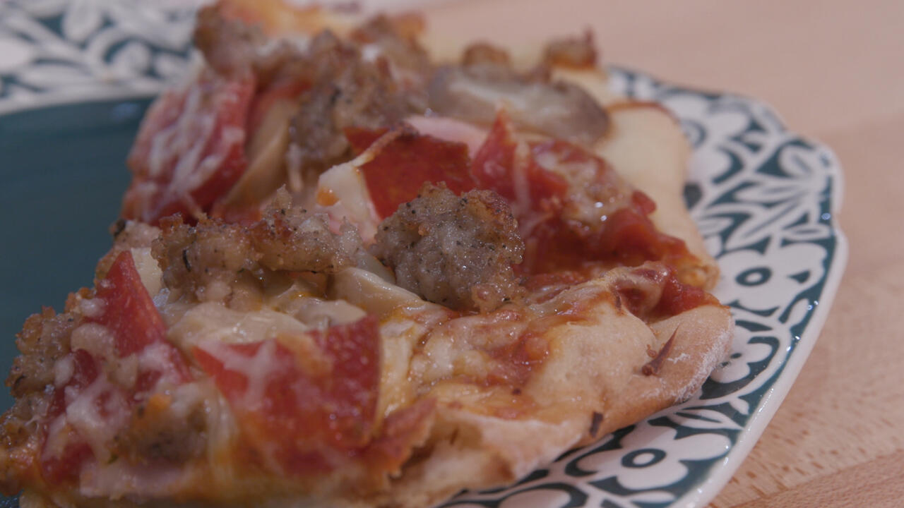 homemade meat pizza on a teal plate with white floral border