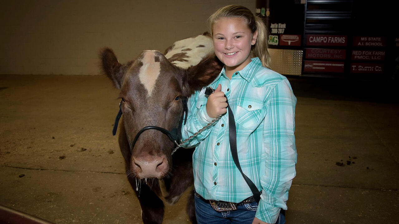 A young girl stands beside a cow at the Mississippi State Fair.