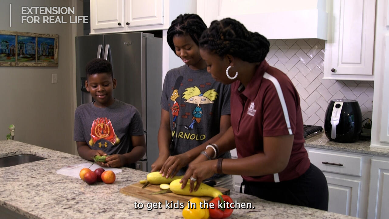 A woman and two children slice vegetables