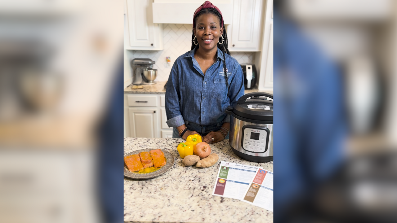 A woman stands in a kitchen with an electric pressure cooker.
