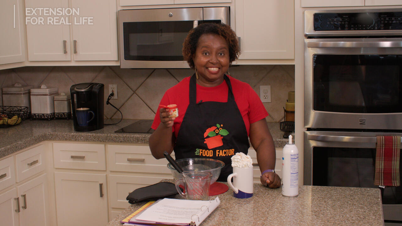 A woman stands at a kitchen counter with a latte.