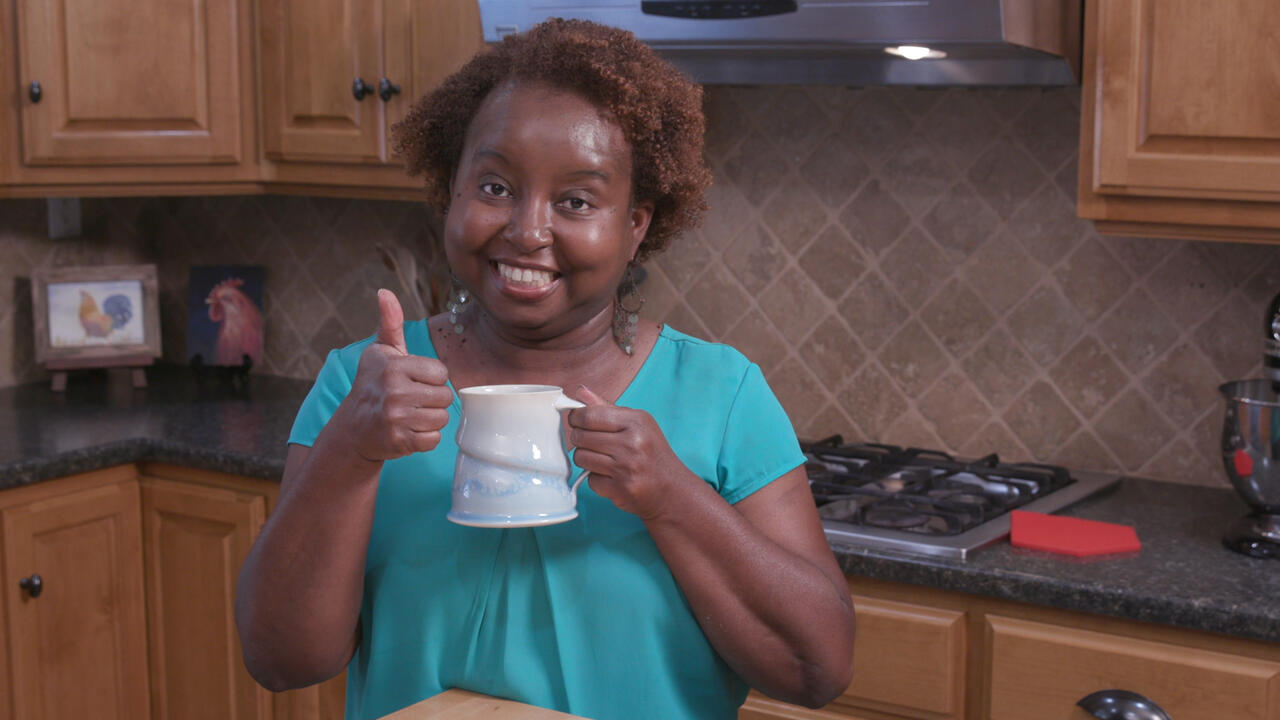 Food Factor host Natasha Haynes holds a mug of cocoa while standing in a kitchen