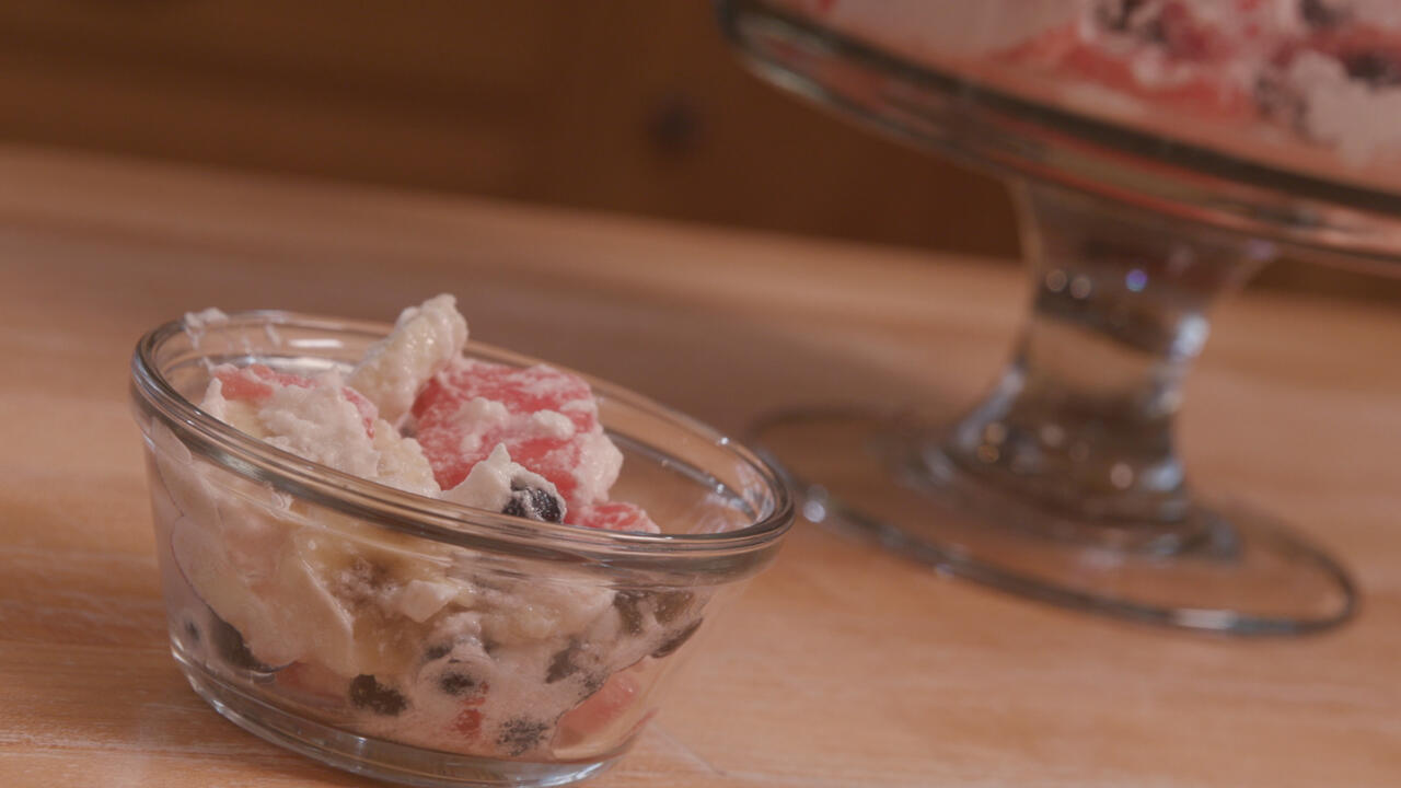 fruit salad with whipped topping in a clear glass bowl