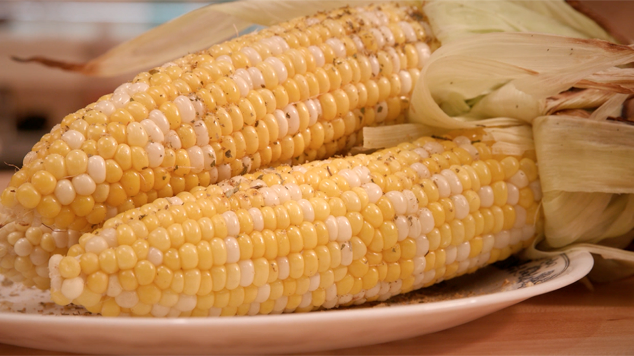 Two ears of seasoned grilled corn on a platter.