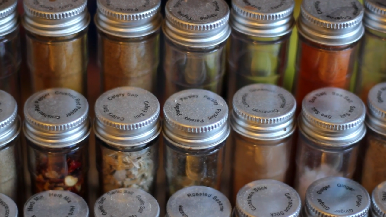 Rows of spices in clear jars with silver tops. 