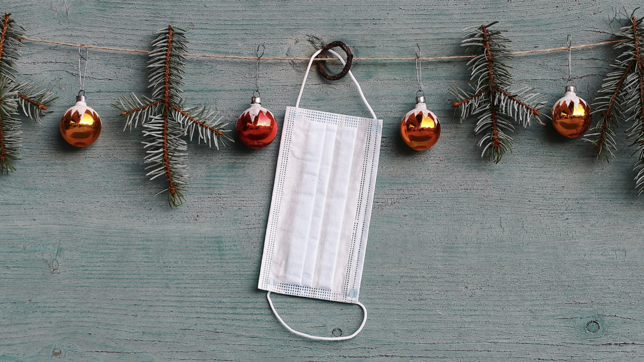 A white mask hanging on Christmas garland.