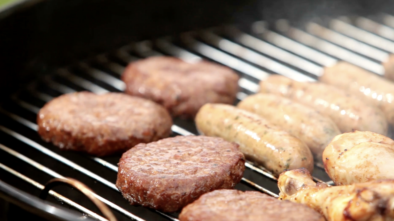 Hamburgers, chicken and hotdogs on a grill.