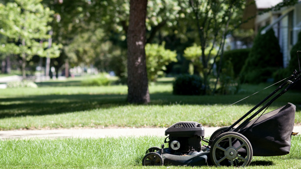A black lawn mower mowing a yard.