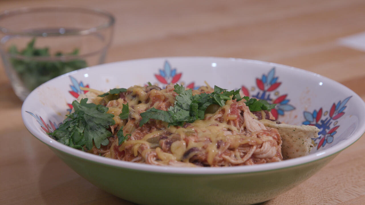Chicken tortilla soup in a colorful bowl with a small glass bowl of cilantro in the background