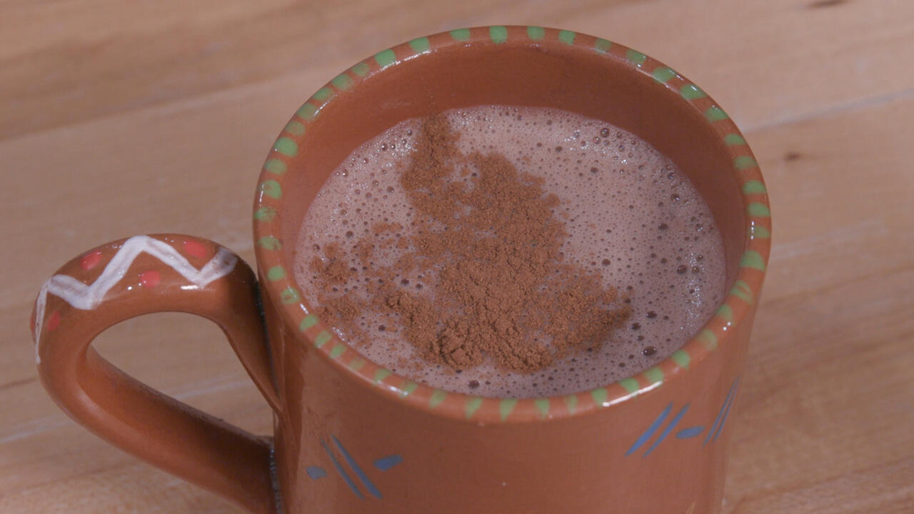Hot cocoa sprinkled with cinnamon in a terra cotta mug
