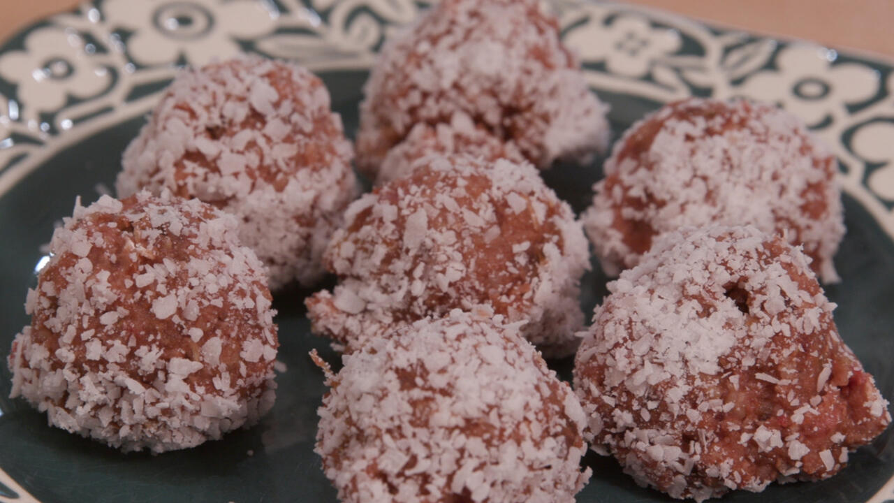 Strawberry cookie dough balls coated in coconut on a plate