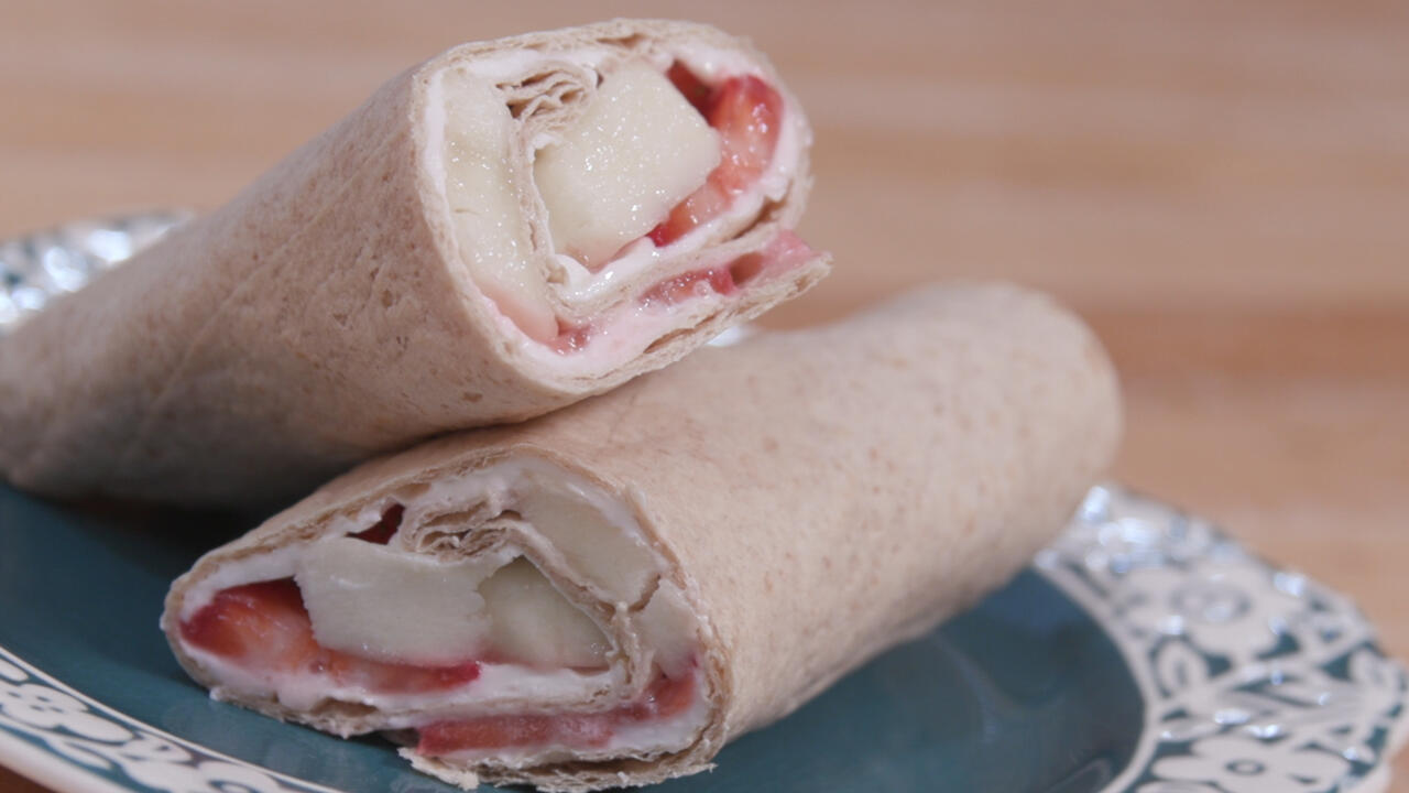 strawberry-banana cheesecake wrap cut in half and displayed on a decorative plate