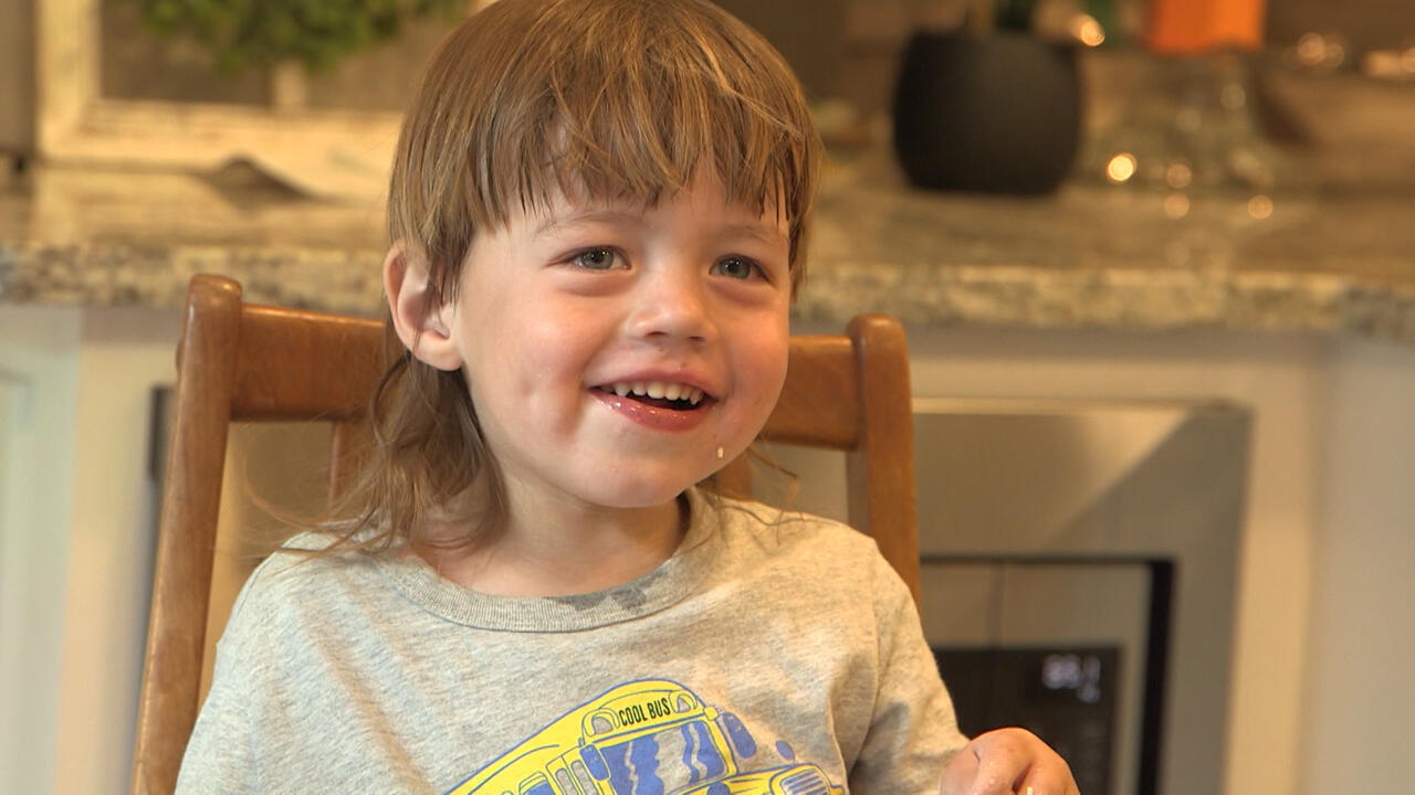 A child smiles at the dining table.