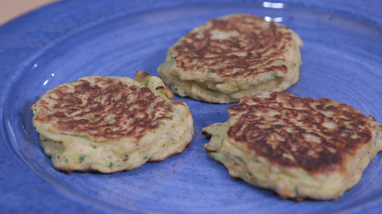 three zucchini fritters on a blue plate