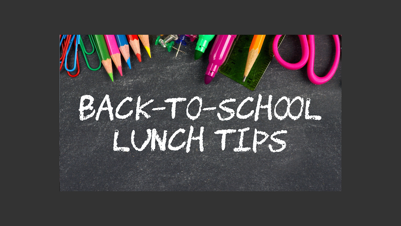 Colored pencils, paper clips, tacks, markers, a ruler, scissors, and a pencil rest at the top of a chalkboard with Back-to-School Lunch Tips written on it in white chalk.