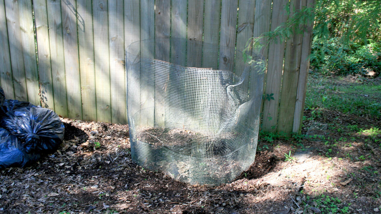 A piece of hardware cloth encircles a small, layered pile of organic waste.