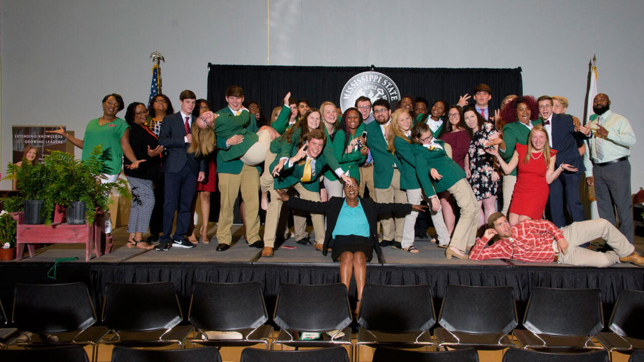 A group of teenagers posing on a stage. 