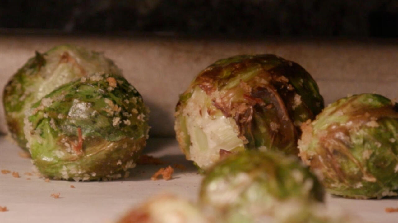 Close-up of roasted Brussels sprouts coated with Panko breadcrumbs on a sheet pan covered with parchment paper. 