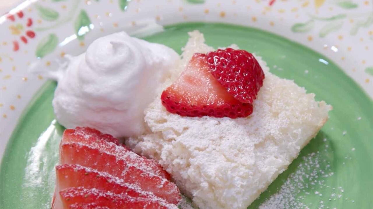 Angel food cake with strawberries, cool whip, and strawberries on a green plate.