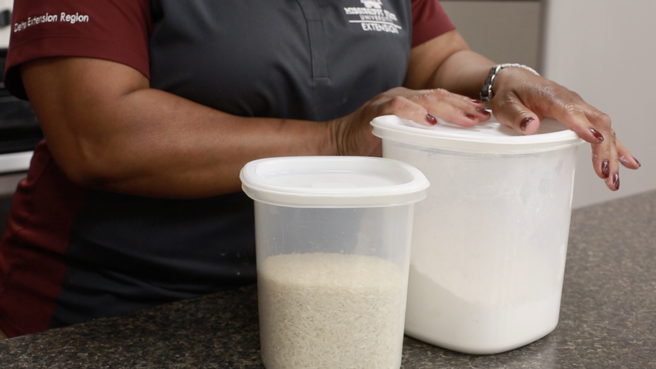 Two partially filled canisters contain rice and flour sit on a speckled black countertop.