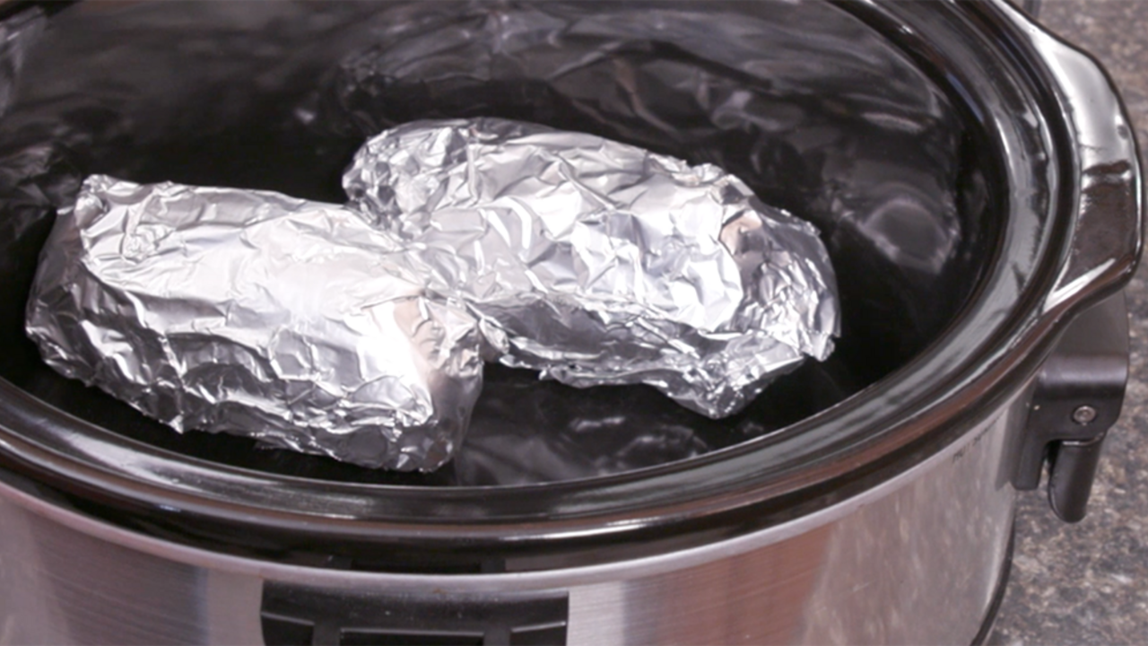Foil wrapped potatoes in a slow cooker.