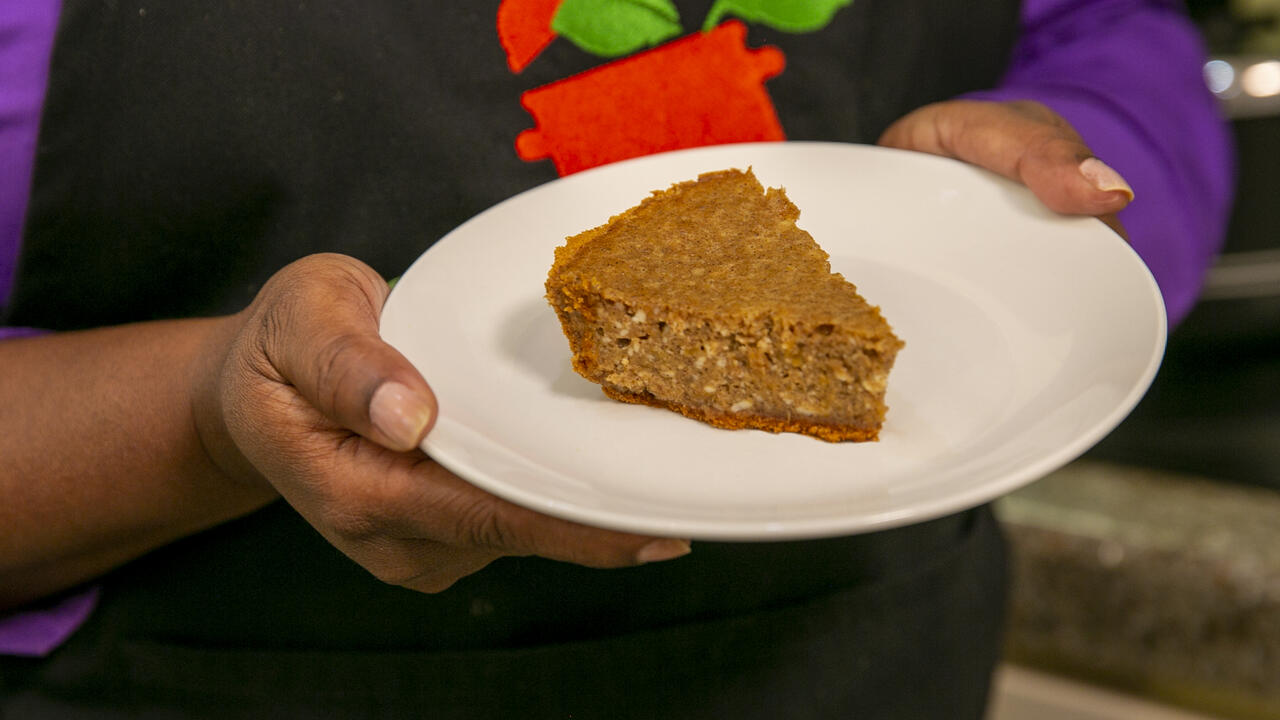 Hands hold a plate with a slice of sweet potato cheese pie