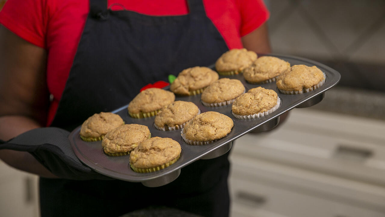 A woman holds a muffin tin full of Peanut Butter Muffins.