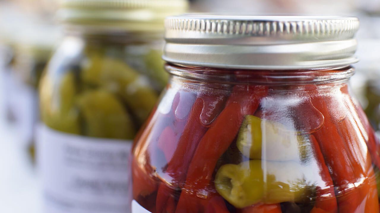 A glass jar with a metal lid is full of vegetables.