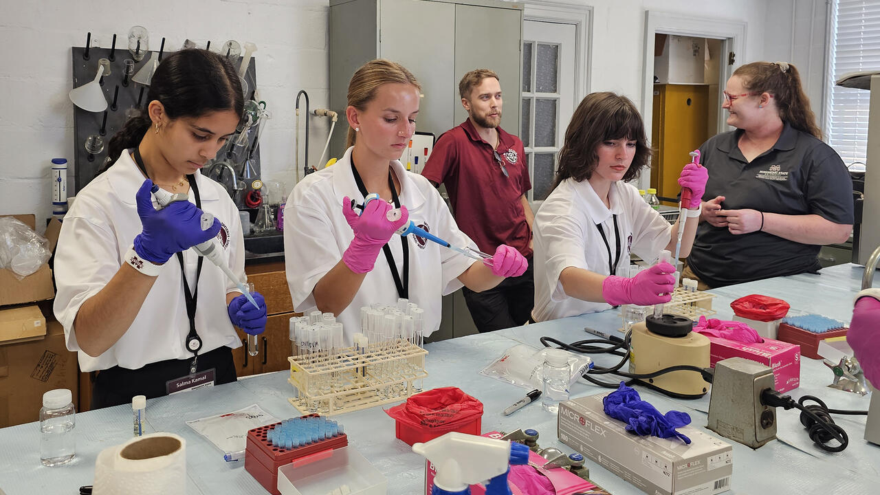 A group of young people use lab equipment in a classroom.