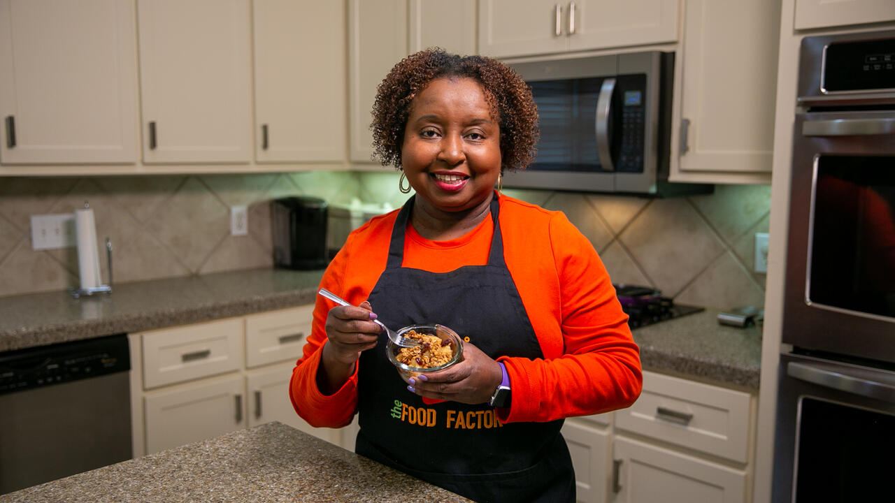 A woman stands in a kitchen and holds a bowl of Cinnamon Fried Pineapple